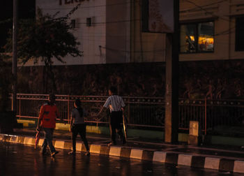 Rear view of people walking on street at night