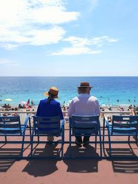 Rear view of people sitting on chair at beach