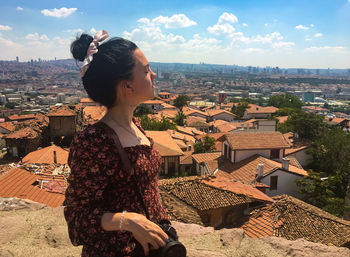 Young woman looking at city buildings against sky
