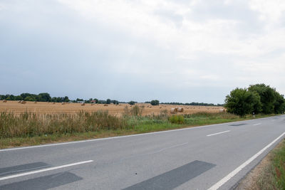 Road by field against sky