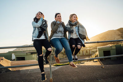 Portrait of happy friends against clear sky