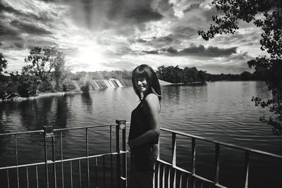 Woman standing by railing against lake