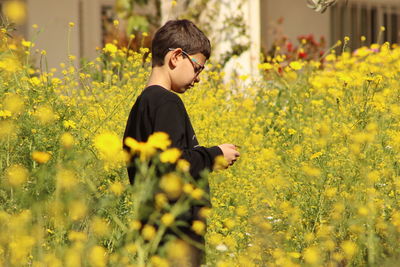 Man standing amidst yellow flowering plants on field