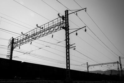 Low angle view of silhouette electricity pylon against sky