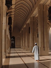 Rear view of man walking in mosque corridor