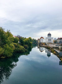 Reflection of buildings and trees in lake against sky