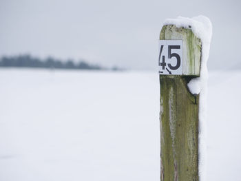 Wooden pole on snow covered landscape