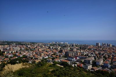 High angle view of townscape by sea against clear sky