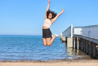 Woman jumping in sea against clear sky