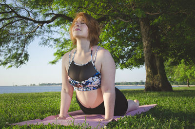 Low angle view of woman doing cobra pose on exercise mat at park