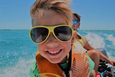 Close-up portrait of smiling boy wearing sunglasses while traveling in boat
