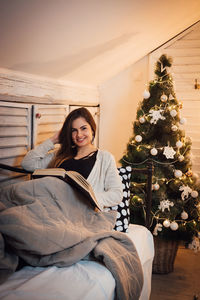 Portrait of smiling young woman sitting by tree