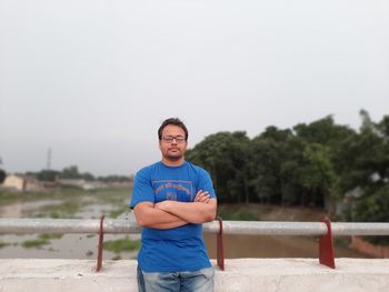 Portrait of young man standing against sky