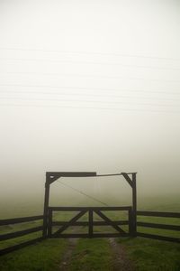 Gate on land against sky during foggy weather