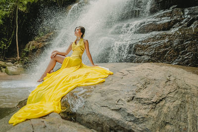 Portrait of woman in water splashing on rock