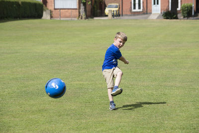 Boy kicking soccer ball on grassy field