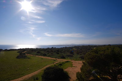 Scenic view of green landscape and sea against sky