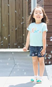 Cute girl smiling while standing against wall