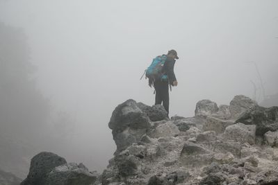 Low angle view of man climbing on rock against sky