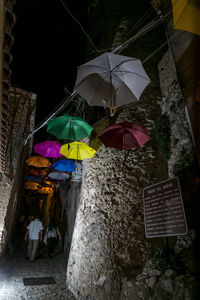 Low angle view of multi colored umbrellas hanging on building