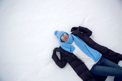 Girl in winter clothes lying on a frozen lake