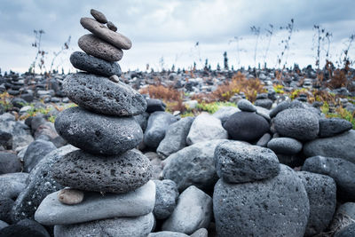 Stack of pebbles on shore against sky