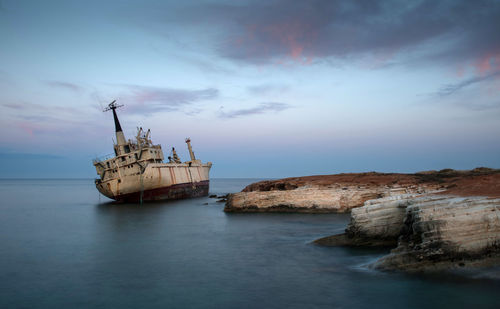 Abandoned boat in sea against sky