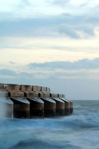 Wooden posts in sea against sky