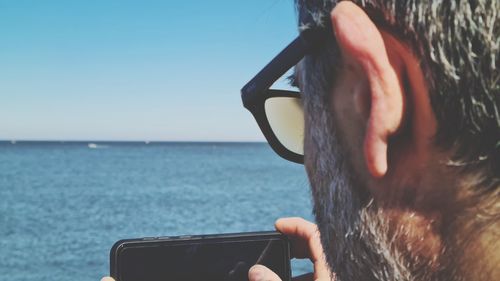 Midsection of man photographing sea against sky