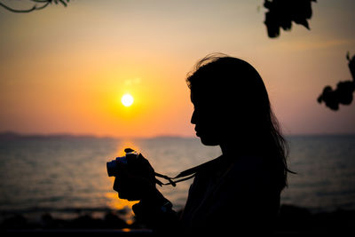 Silhouette woman on beach against sky during sunset