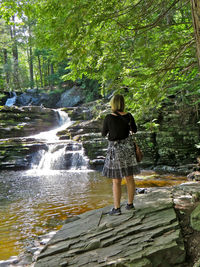 Rear view of woman standing in forest