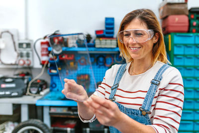 Female mechanic with security glasses touching transparent tablet