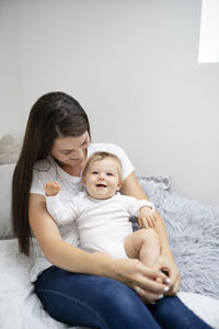 Mother and daughter sitting on bed at home