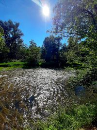 Scenic view of waterfall against sky on sunny day