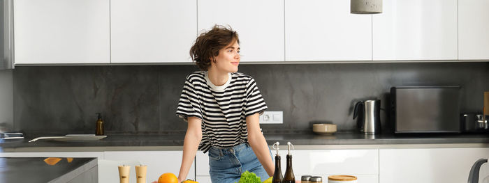 Portrait of young woman standing in kitchen