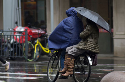 Midsection of two people on a bicycle on a rainy day