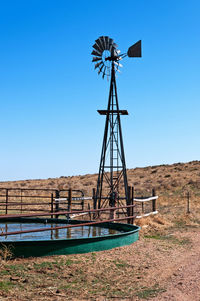 Traditional windmill on field against clear blue sky