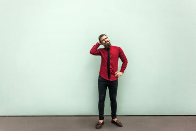 Full length portrait of young woman standing against wall