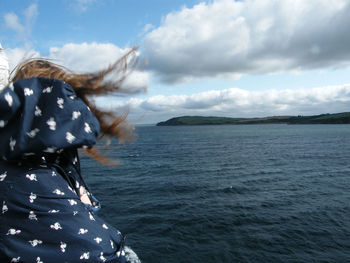 Rear view of woman by sea against sky