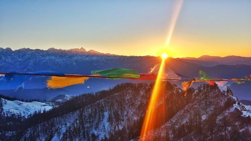 Colorful prayer flags waving against snowcapped mountains during sunset