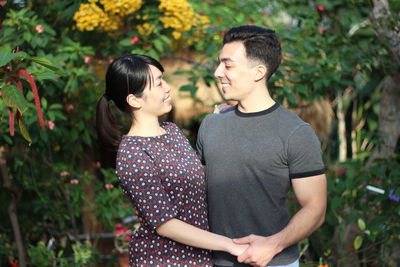 Young couple standing against plants