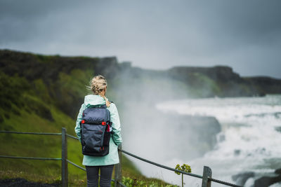 Blond woman visit gullfoss waterfall in iceland. famous place to visit on golden circle, iceland