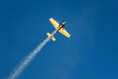 Low angle view of airplane flying against clear blue sky