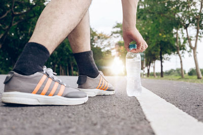 Low section of man having water in bottle on road