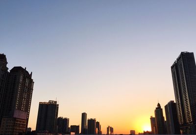 Low angle view of buildings against clear sky during sunset