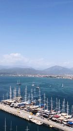 Sailboats moored at harbor against blue sky