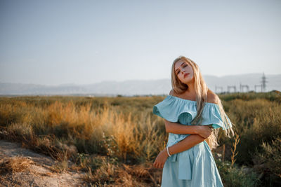 Portrait of teenage girl wearing dress standing on land against sky