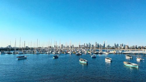 Boats in sea against clear blue sky