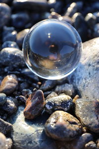 Close-up of crystal ball with reflection of woman on stones