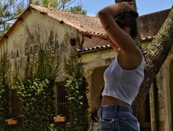 Side view of young woman sanding by house in town